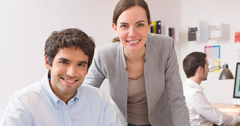 Two smiling professionals working together in office