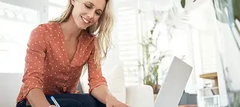 Smiling professional woman with laptop writing notes