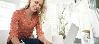 Smiling professional woman with laptop writing notes
