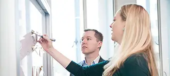 Two professionals strategising at a whiteboard